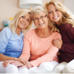 Three generations of women sit on a couch