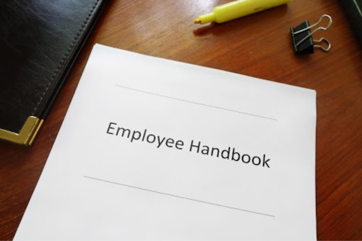 Employee Handbook on a desk with highlighter, clip, and other binders