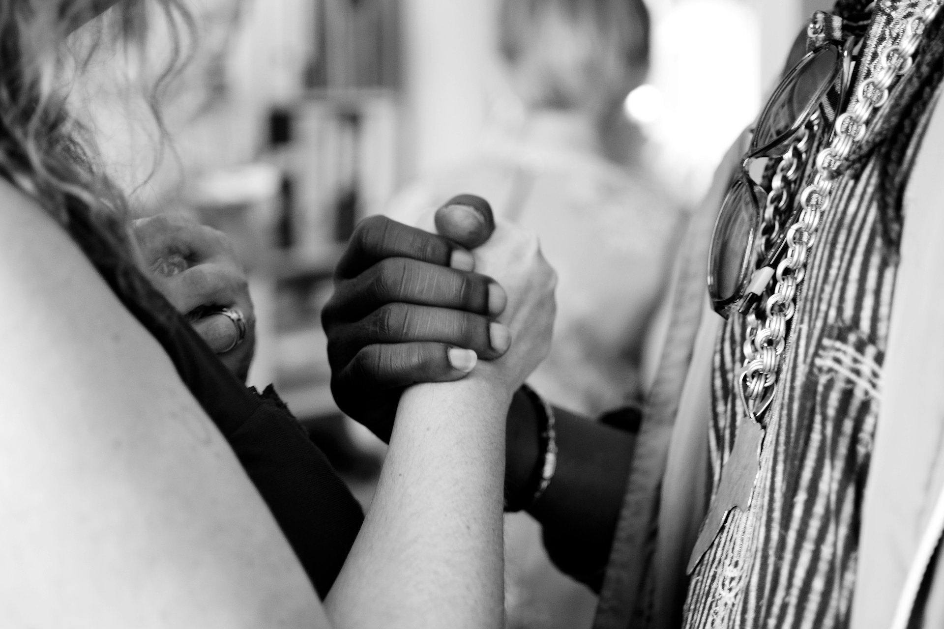Two people, one of white race and one of black race, clasping hands, black and white photo.